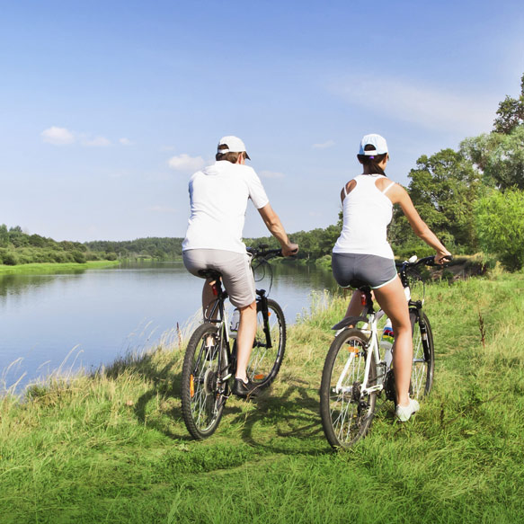 Couple riding bike by lake